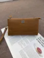 Braune kleine Leder-Reißverschlusstasche mit Handschlaufe und Klee-Metall-Detail. - Braun