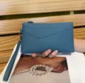 Primo piano dettagliato della borsa pochette da donna in pelle blu, texture e cerniera. - Blu