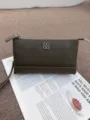 Detaillierte Nahaufnahme der eleganten dunkelgrünen Umhängetasche mit stilvollem Kleeblattlogo. - Khaki