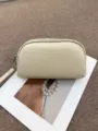 Minimalist leather clutch detail showing beige texture, metal zipper and wrist strap. - Off White