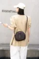Detail view of the retro genuine leather round crossbody bag, showing fine texture and strap. - Coffee