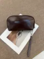 Dark brown leather cosmetic bag detail showing semi-arc shape, zipper and wristlet strap. - 22*5.5*12CM / Wine Coffee