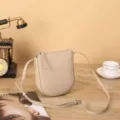 Vue détaillée d'un petit sac bandoulière beige minimaliste, montrant la texture et l'anse. - 16x19x5cm / Abricot