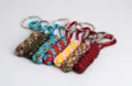Close-up of handmade woven paracord keychains with metal carabiners in various vibrant colors. - Woven Paracord Keychain