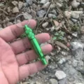 Green aluminum outdoor survival whistle featuring a waterproof compartment and key ring. - Green