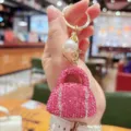 Close-up detail of the sparkling pink rhinestone handbag keychain with pearl charm and gold hardware. - Deep Pink