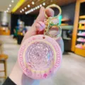 Detailed view of a pink glowing UFO keychain pendant, featuring a starry light and metallic ring. - Pink