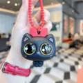 Primo piano dettaglio del portachiavi gatto nero carino con fiocco rosso, giocattolo silicone. - Nero