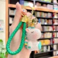 Detailed shot of cute resin unicorn keychain with green braided strap and gold bell charm. - Green