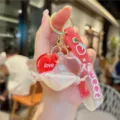 Close-up detail of creative oil-filled quicksand heart keychain with cute wings and strap. - White