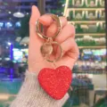Primo piano dettagliato del portachiavi a cuore in strass rossi con anello dorato. - Rosso