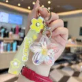 Detailed view of the clear liquid floating flower keychain with a yellow Sakura strap. - Yellow