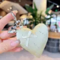 Close-up of a charming satin heart keychain with sparkling rhinestones and a sweet bow detail. - Yellow