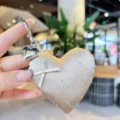 Close-up of sparkling rhinestone satin heart bag charm and keychain detail with cute mini bow. - Coffee