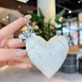White satin heart bag charm with bows and rhinestones detail close-up view accessory - White