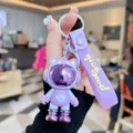 Leuke paarse astronaut sleutelhanger met band, stijlvolle PVC cartoon rugzakhanger voor studenten. - Paars