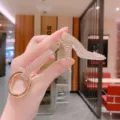 Close-up of sparkling rhinestone high heel keychain with gold ring and crystal details. - Solid Pink