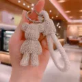 Rhinestone bear keychain detail view, featuring sparkling crystals and white braided strap. - White