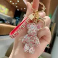 Primo piano dettagliato di un portachiavi orsetto di strass scintillante con cinturino. - Rosa Misto
