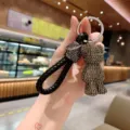 Detail view of sparkly rhinestone crystal bear keychain with black leather strap and rings. - Black