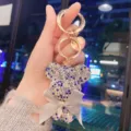 Detailed view of the rhinestone bear keychain featuring a stylish bow and letter charm. - Mixed Blue