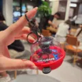Close-up detail view of a creative mini basketball hoop keychain toy inside clear capsule. - Black Basket No Sound Light