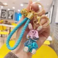 Dettaglio portachiavi coniglietto in strass, ciondolo in metallo galvanizzato con cinturino intrecciato. - Rosa E Blu