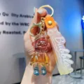 Close-up view of translucent resin cartoon character keychain with colorful strap and sturdy rings. - Orange