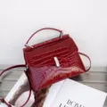 Red crocodile texture handbag detail, elegant top handle and metal clasp design for women. - Red