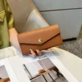 Detail view of a stylish brown leather long wallet for women, elegant envelope design. - Earthy Yellow