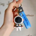 Detail van cartoon blok astronaut sleutelhanger met blauwe riem en metalen ring voor tasauto. - Zwarte Ruimtevaarder