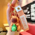Close-up detail shot of cute cartoon capybara holding turtle keychain with silicone strap. - Capybara with Turtle