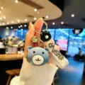 Close-up detail of a cute blue bear acrylic keychain and bag charm with a bear strap. - Gray