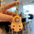Close-up detail of the cute blowing bubbles capybara keychain, soft material and gold ring. - Yellow