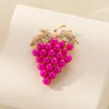 Primer plano de un bonito broche en forma de uva con pedrería brillante y perlas. - Fucsia Perla Artificial Uva