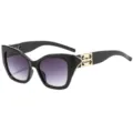 Stijlvolle zwarte cat-eye zonnebril met paarse verlooplenzen en gouden tempeldetails. - Zwart Frame Verloop Grijze Lenzen