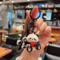 Close-up detail of a cute cartoon panda keychain with red apple pendant and black strap. - Electroplated Panda - Apple
