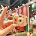 Close-up detail of the cute capybara projection camera keychain with a bell pendant. - Capybara Camera - Apple