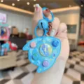 Detailed shot of the cute blue cartoon rocket electronic game console toy keychain with buttons. - Blue