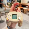 Close-up detail of cute capybara electronic game console keychain with mini screen and buttons. - Whack-A-Mole Style—Yellow Car