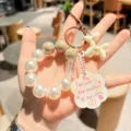 Nahaufnahme eines süßen Acryl-Schlüsselanhängers mit Perlenarmband und weißem Ballonhund. - Weißer Welpe