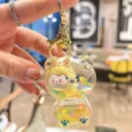 Closeup of transparent liquid glitter bear keychain with cute cartoon character inside gold ring. - Yellow