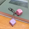 Detailed shot of a creative colorful macaron dice keychain, pink and purple pendants. - Pink + Purple