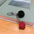 Close-up detail of a creative black and red dice keychain with metal clasp on a book. - Black + Red