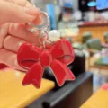 Red bow keychain pendant detail showcasing the glossy acrylic bow and elegant pearl charm ornament. - Dark Red