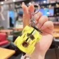 Close-up detail of yellow alloy sports car keychain pendant with wing and body style. - Yellow