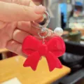 Red bow keychain with pearl pendant, cute acrylic bag charm and phone accessory for women. - Red