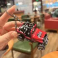 Primo piano dettagliato di un portachiavi a forma di jeep fuoristrada in metallo rosso. - Rosso Vivo