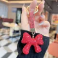 Close-up detail of the glittering red rhinestone bow keychain, showing crystal sparkle and ring. - Bright Red