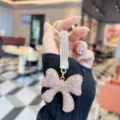 Sparkling rhinestone bow keychain with luxury gold hardware, perfect stylish bag pendant. - Champagne